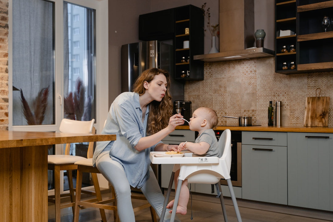 mom feeding child sitting on high chair