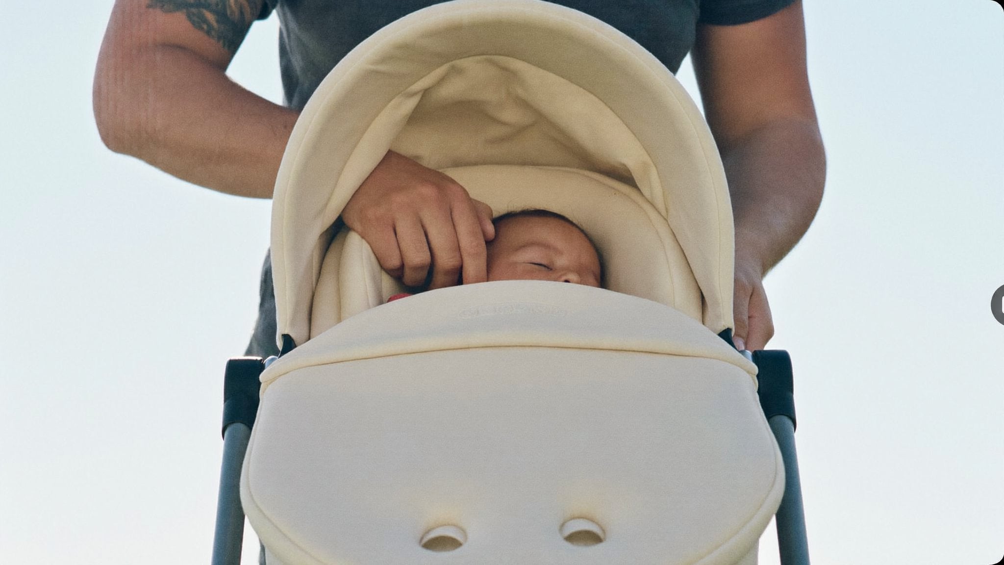 Parent settling a sleeping baby into an infant car seat carrier - Bambinos & Beyond Baby Car Seats (Birth-15m)