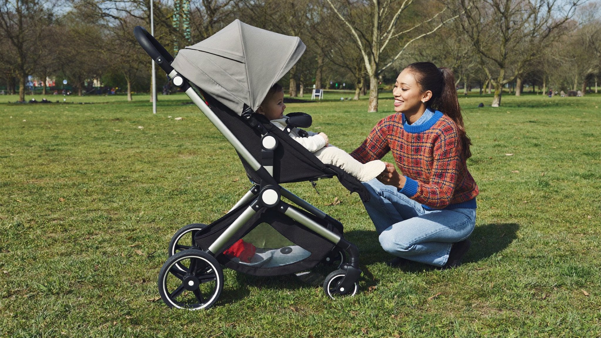 Parent fitting a footmuff to a pram in the park - Bambinos & Beyond Pushchair Accessories